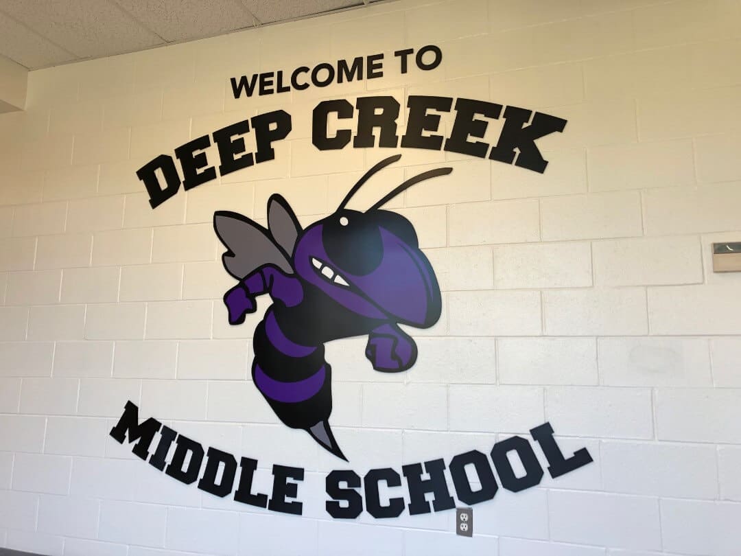 School entrance sign, interior wall logo lettering on brick surface